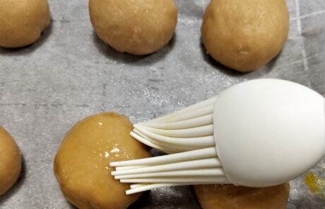 brushing the dough balls with egg wash