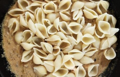 stirring cooked pasta shells in with the sauce